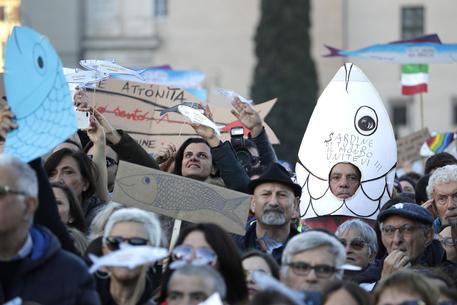 A demonstrator shows a sardine-shaped banner reading "Sardines of the world unite" during a gathering in St. John at the Lateran Square of the "Sardines", an Italian grass-roots movement against right-wing populism, in central Rome, Saturday, Dec. 14, 2019. (ANSA/AP Photo/Gregorio Borgia) [CopyrightNotice: Copyright 2019 The Associated Press. All rights reserved.]